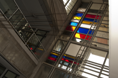 818254 Afbeelding van een aantal gekleurde glasvlakken doorsneden door staalkabels in de hal van het kantoorgebouw van ...